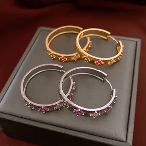 Gold and silver textured hoop earrings with colorful gemstone floral patterns