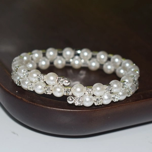 Detailed close-up of double-layer spiral bracelet with white pearls and sparkling rhinestones