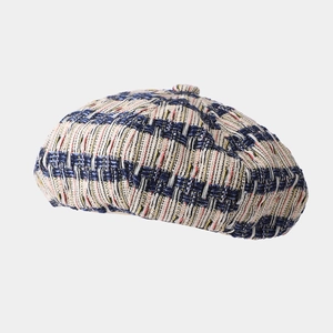 Detail of tweed beret showing blue and beige contrast woven texture and top button