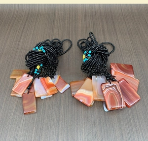 Detail view of rectangular red agate pendants with natural stripe patterns and beaded cords