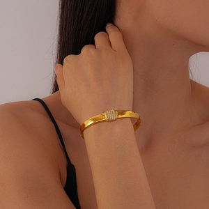 Detail eines goldenen Edelstahl-Armreifs mit Diamanten am Handgelenk eines Models
