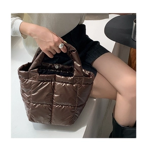 Detail view of a dark brown quilted down tote bag with wide soft handles for winter