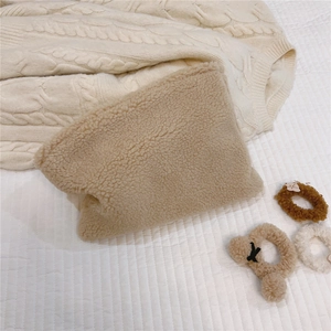 Close-up of soft beige faux shearling makeup bag featuring plush warm fleece texture