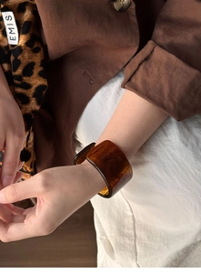Detail of wide tortoiseshell resin bangle with a polished finish on model wrist