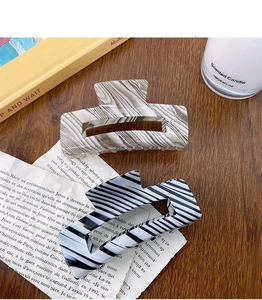 Macro shot of marble and geometric stripe acetate hair claws on a rustic wooden desk
