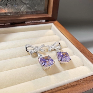 Detailed close-up of bow-knot silver earrings featuring square purple zircon gemstones