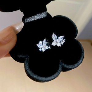 Macro shot of silver butterfly stud earrings with zircon stones in a black flower box