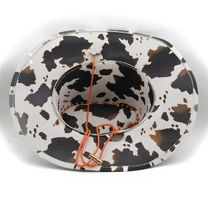 Detail eines Cowboyhuts mit Kuhmuster, Innenkrempe und orangem Band mit goldener Schnalle