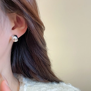 Polished silver half-hoop earring shown on model with smooth mirror finish metal texture