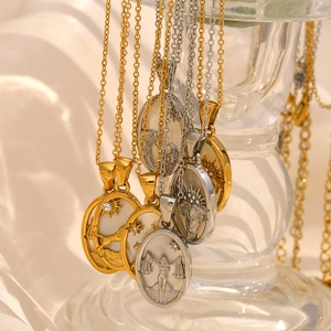 Detail of 18K gold and silver zodiac necklaces with shell inlay on a glass holder