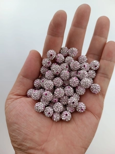 Detailed view of 10mm pink disco clay beads with sparkling white rhinestones held by hand
