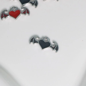 Detailed macro view of gothic heart charms with silver wings in red and black enamel