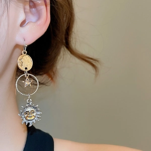 Dettaglio di orecchini asimmetrici boho con sole e luna indossati da una modella
