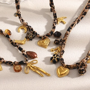 Détail de colliers léopard en tissu avec pendentifs cœur et lune dorés sur tissu beige