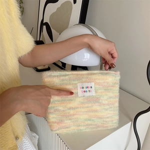 Detailed macro of a soft plush makeup bag with colorful rainbow knit texture and a label