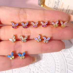 Macro shot of colorful zircon butterfly earrings held by hand in a refined lifestyle setting