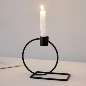 Modern black geometric metal candle holder with a white spiral candle on a table