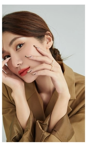 Detail of two gold pearl rings with pavé stones worn by a model in a beige suit
