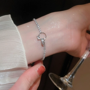 Macro view of knotted zircon bracelet on wrist with elegant high-heeled glass background
