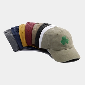 Dettaglio di berretti vintage in cotone lavato in vari colori con ricamo a quadrifoglio
