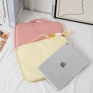 Detailed view of pink and beige waterproof laptop bags with woven handles on white cloth