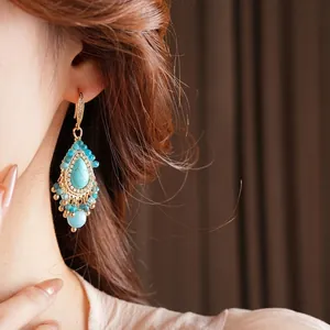 Boucles d'oreilles dorées avec pierres turquoise et élégants pompons de perles