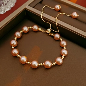 Detailed shot of adjustable gold pearl bracelet with pink pearls in a premium jewelry box