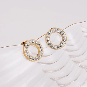 Boucles d'oreilles rondes dorées classiques serties de strass sur un fond texturé