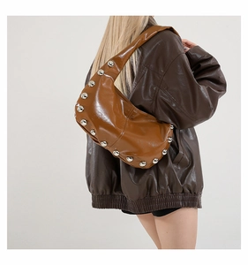Detail of caramel brown patent leather hobo bag with large silver stud embellishments