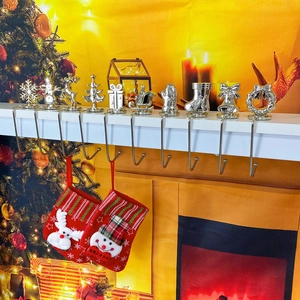 Silver metal Christmas stocking hangers with snowflake and reindeer motifs on a mantel