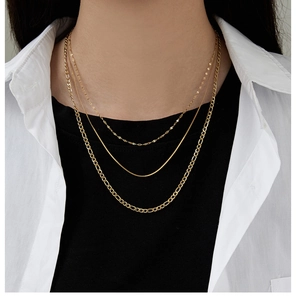 Close-up of gold titanium steel layered necklaces on model showing varied chain textures