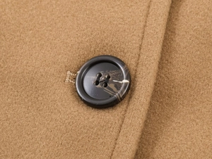 Detail of camel wool blend fabric with tortoise shell textured button on coat