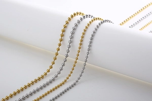 Close-up of gold and silver beaded titanium steel chains on white podium display