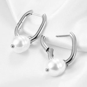 Close-up of silver U-shaped stainless steel earrings with drop-shaped white pearls