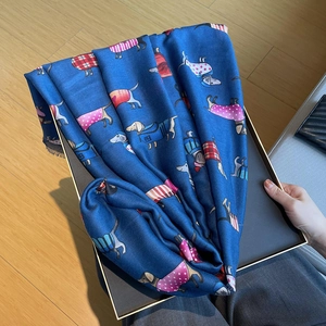 Detail of blue cotton-linen scarf with cartoon dachshund prints in a gift box