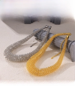 Close-up of gold and silver spring coil necklaces with PVD plating on a stone pedestal