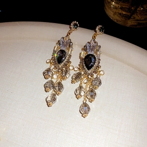 Makroaufnahme von Vintage-Gold-Ohrringen mit dunklen Tropfensteinen und Kristallen