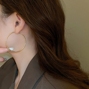 Close-up of model wearing large minimalist golden hoop earrings in a stylish fashion shot