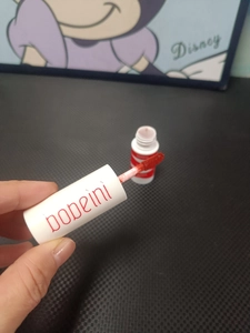 Detailed shot of the applicator brush with matte red liquid lipstick and sleek white bottle