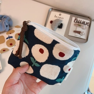 Detail of dark blue floral linen coin purse with white zipper and cord pull handle