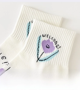 Détail des poignets côtelés élastiques sur chaussettes blanches avec fleur mauve et broderie