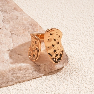 Detailed view of golden open ring featuring a hammered metal texture on a stone background