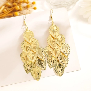 Détail de boucles d'oreilles dorées multicouches avec feuilles de style bohème sur blanc