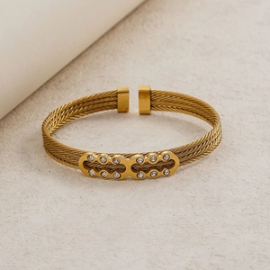 Elegant gold-tone braided cable cuff bracelet featuring a crystal-encrusted center plate