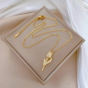 Gros plan d'un pendentif tulipe doré à l'or 18 carats avec cristaux pavés sur soie