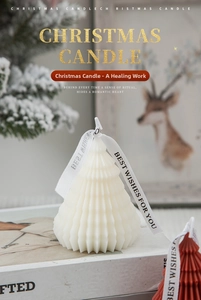 Macro detail of red and white origami Christmas tree candles with Merry Christmas ribbons