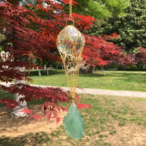 Hanging crystal suncatcher with golden metal chain and green agate stone in nature