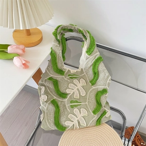 Détail du sac cabas vert sauge avec broderies florales 3D et finitions à franges