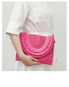Detail of rose red woven straw envelope bag with multi-layer tassel trim and texture