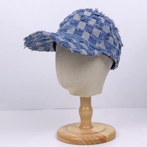 Blue and white checkered denim baseball cap with distressed frayed edges on a mannequin